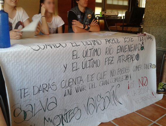 Los participantes en el programa muestran una pancarta reivindicativa contra el abuso de recursos naturales