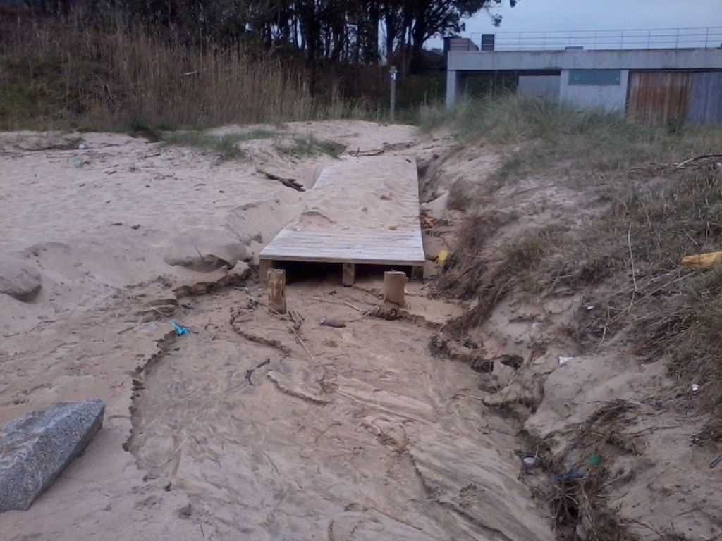 Desplazamiento de la pasarela de madera y cauce de agua y ducha en la playa de Esteiro