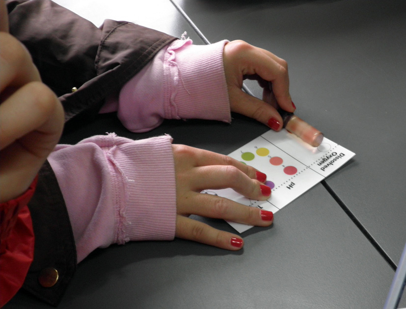 Mediante una clave de identificación por colores, una alumna calcula el ph de una muestra de agua